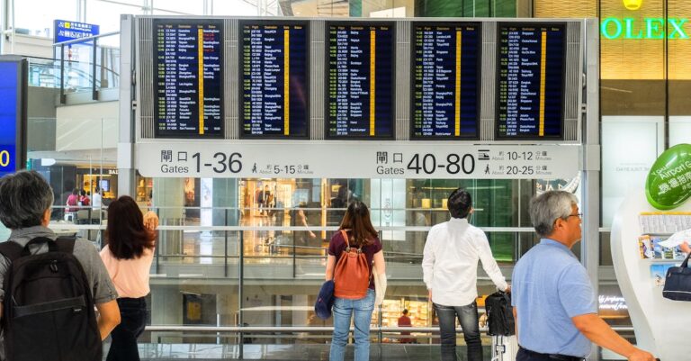 Passengers checking the departure board at Hong Kong International Airport terminal.