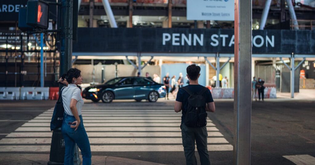 Two people wait at a pedestrian crossing near Penn Station in New York City, capturing urban life.