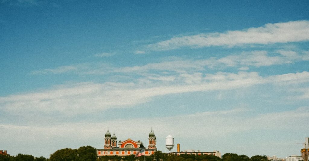 Scenic view of Ellis Island as the American flag waves, set against a clear blue sky.