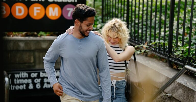 Smiling couple exiting Bryant Park metro station in New York City on a sunny day.