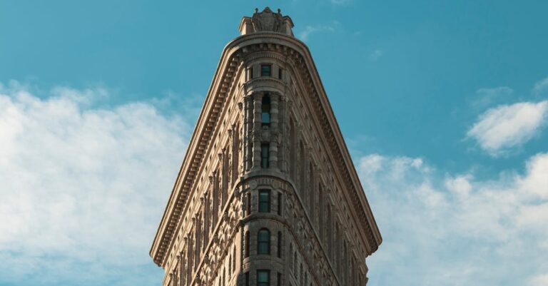 Flatiron Building in New York City under a bright sky, showcasing its unique architecture.