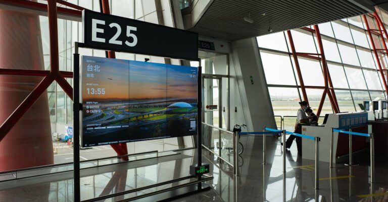 A view of a modern airport terminal showcasing Gate E25 with a flight display board.