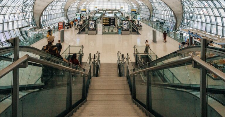 Spacious modern airport terminal featuring a glass dome design and descending stairway view.