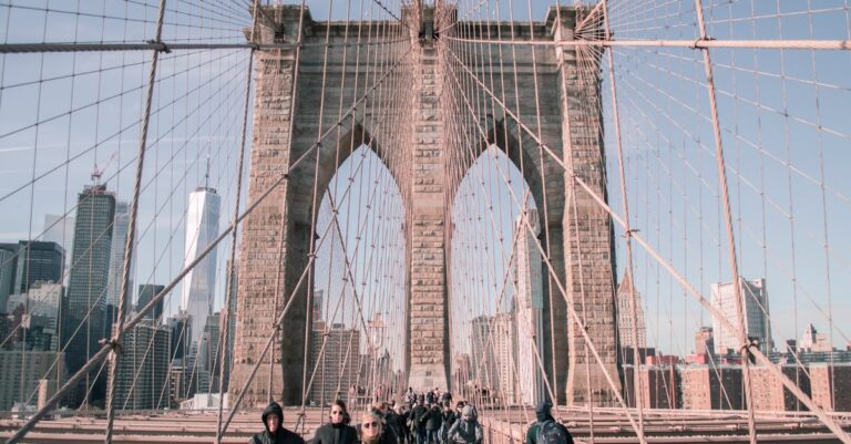 Bustling scene on Brooklyn Bridge with city skyline and pedestrians.