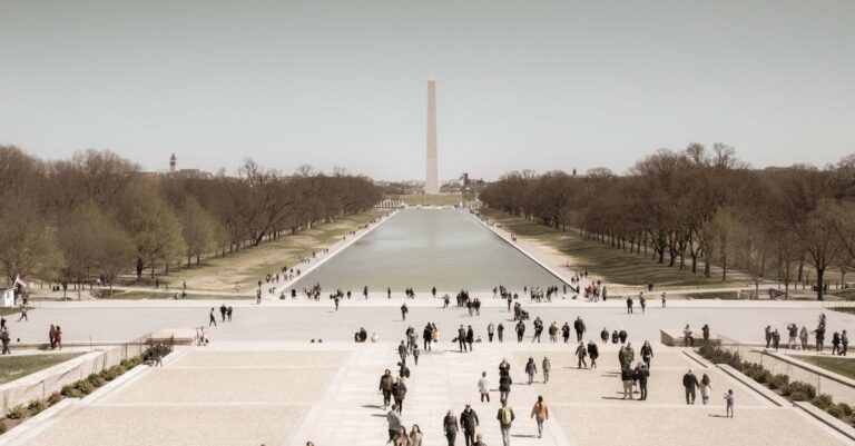 A crowd enjoys a sunny day at the Washington Monument Reflection Pool, a popular tourist spot in Washington, D.C.