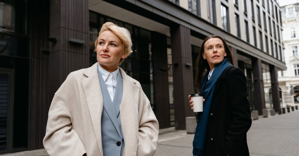 Two women in stylish professional attire walking in a modern urban environment.