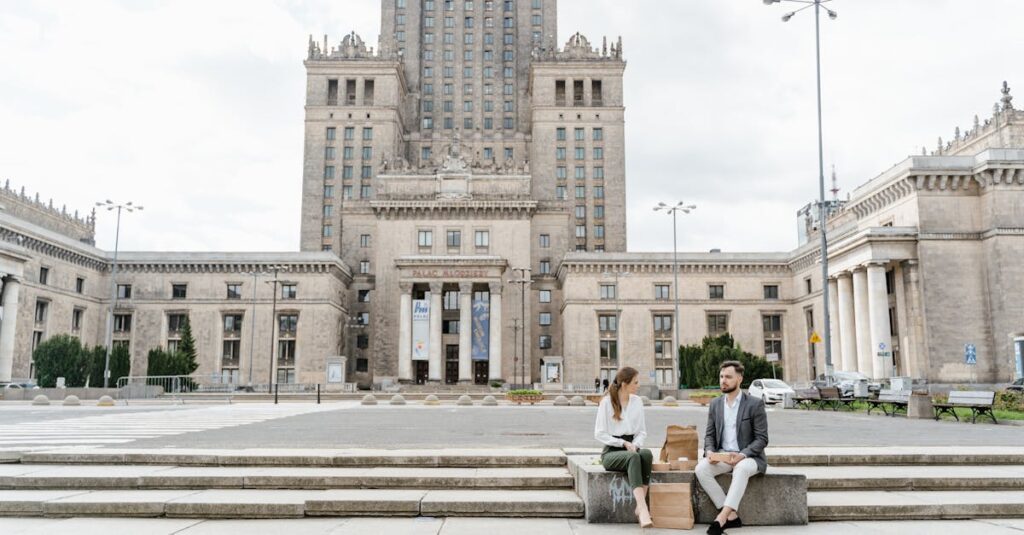 Two colleagues enjoy lunch on steps of Warsaw's Palace of Culture and Science.