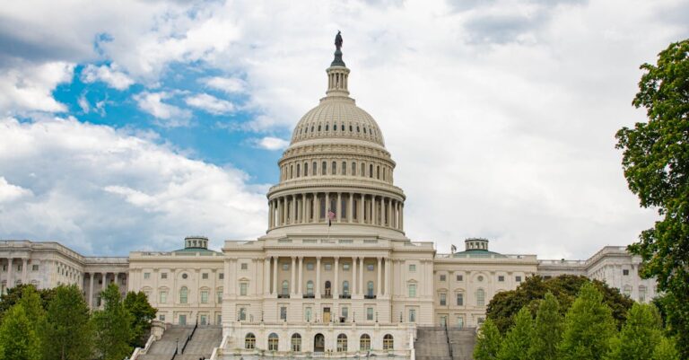 View of United States Capitol with neoclassical architecture against a cloudy sky in Washington D.C.