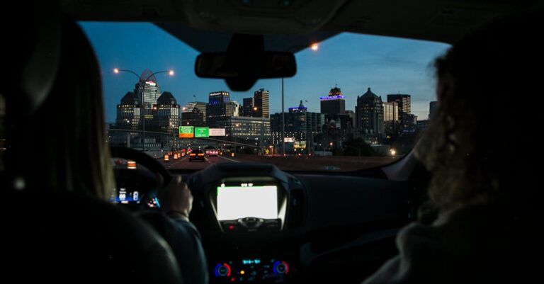 View of city skyline during night drive, captured through car windshield.