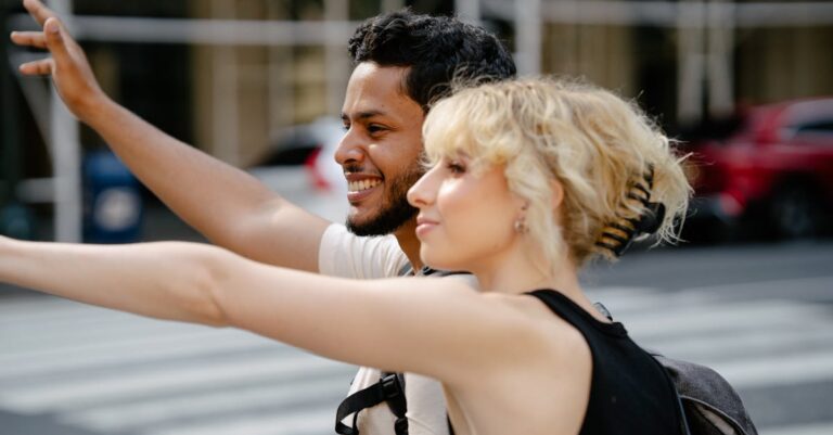 A cheerful couple waves for a ride on a sunny urban street. Perfect for lifestyle themes.