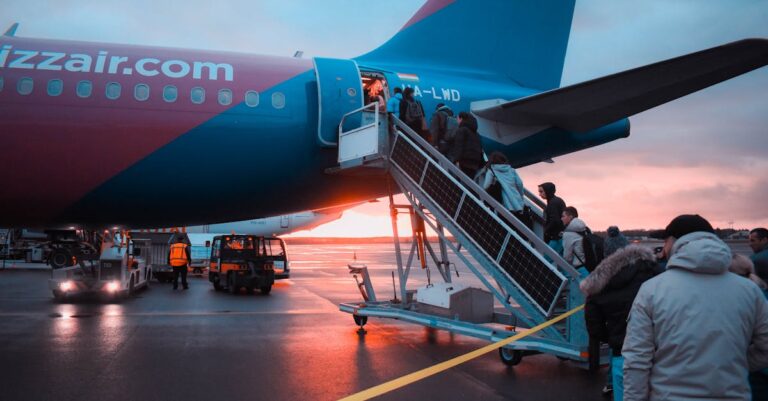 Passengers boarding an airplane at sunset with a vivid sky in the background, capturing a travel moment.