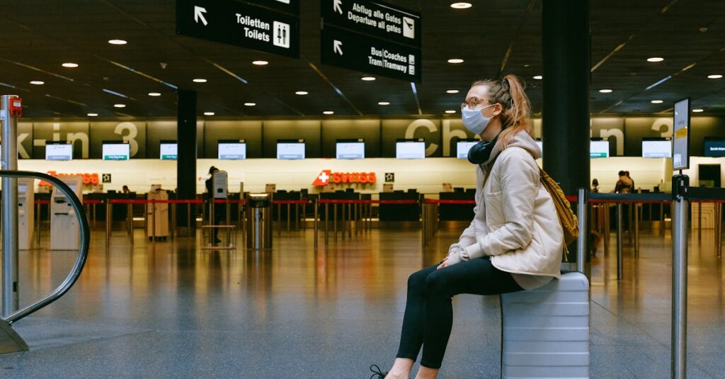 Luxury Bus New York - 8 Advantages You Can’t Skip 3 A woman wearing a face mask sits on luggage in an airport terminal amid the pandemic.