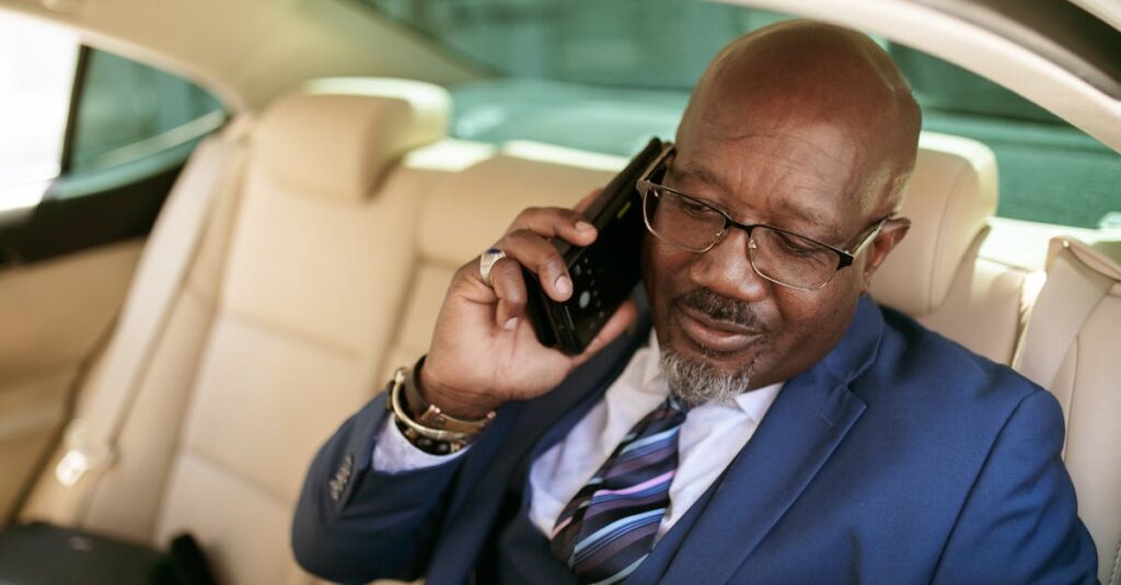 Mature businessman in a suit talking on a smartphone while seated in a luxurious car.