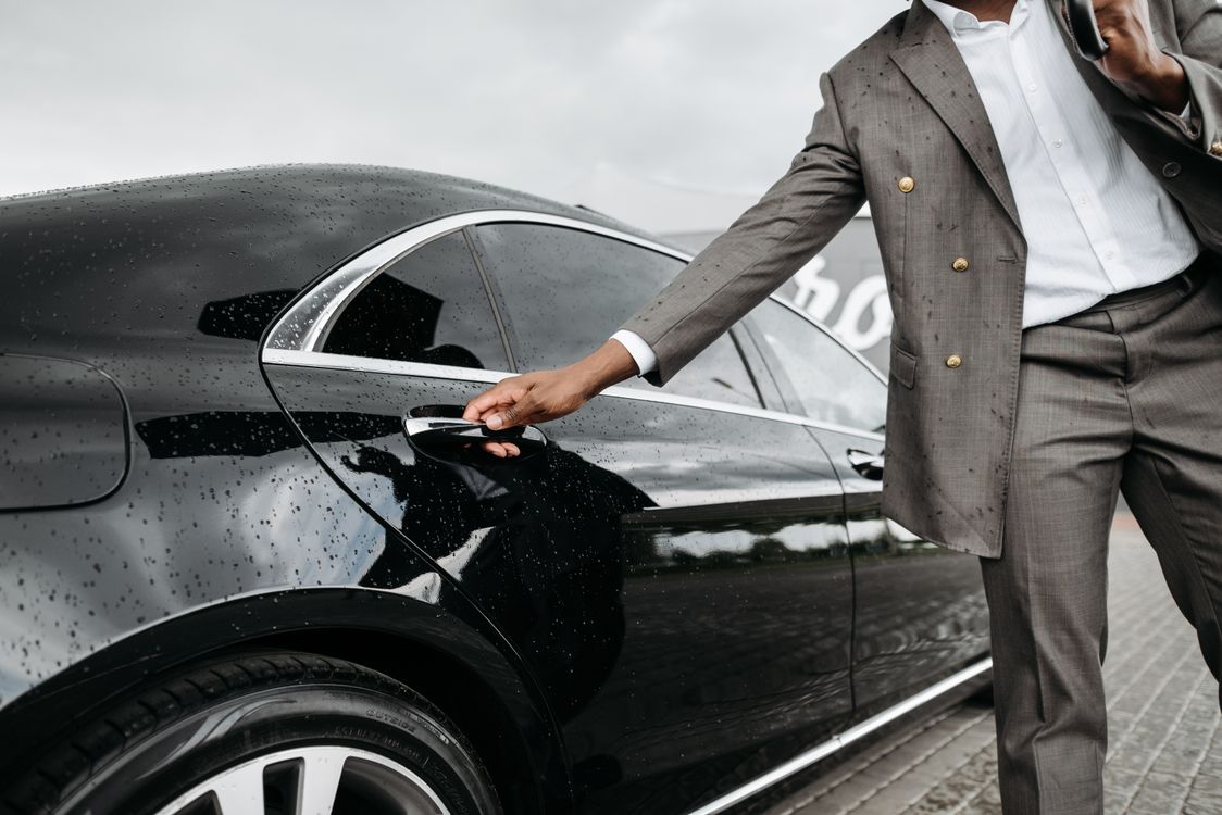 limousine service new york — chauffeur opening the door of a black limousine