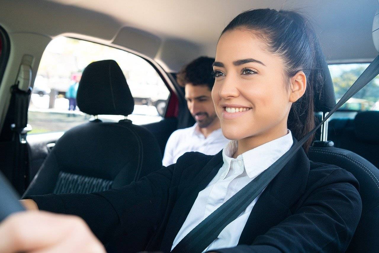 Smiling woman driving with a passenger in the back seat