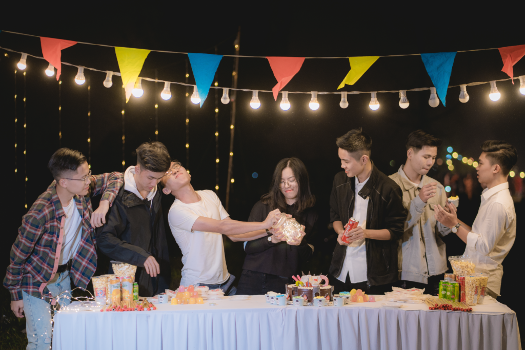 A lively group of friends enjoying a night party outdoors with food and decorations.