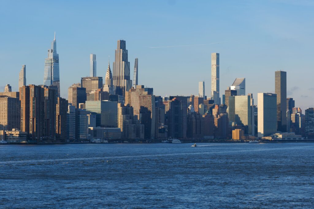 A stunning view of Manhattan skyline at sunset, showcasing iconic skyscrapers under a clear blue sky.