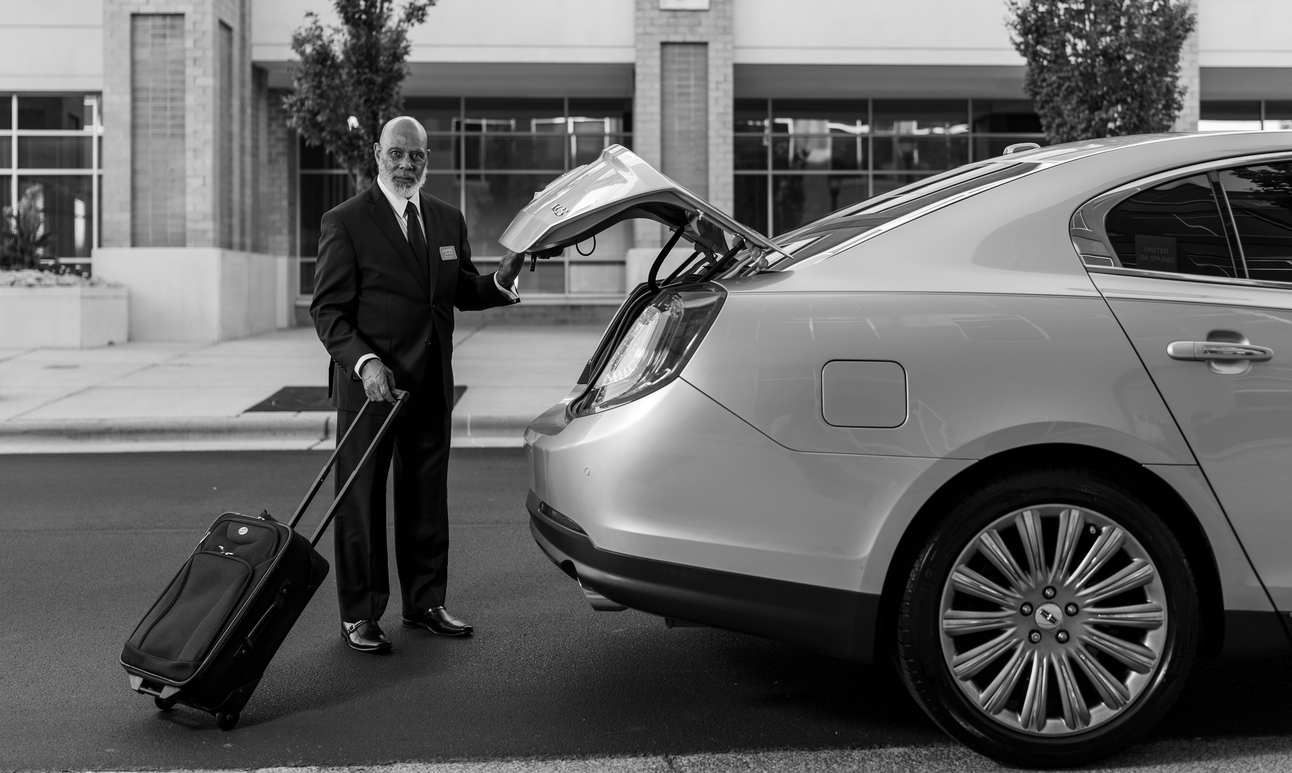 Chauffeur service New York — professional chauffeur with black sedan