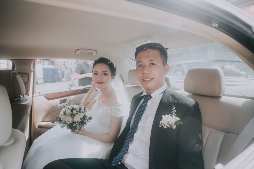 Joyful newlywed couple smiling inside a decorated wedding car